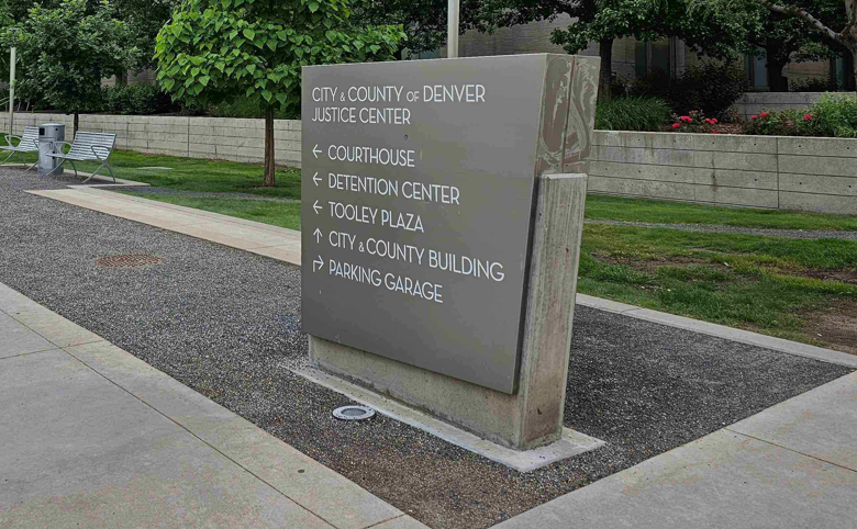 City and County of Denver Justice Center directional sign indicating locations for the courthouse, detention center, Tooley Plaza, city and county building, and parking garage.