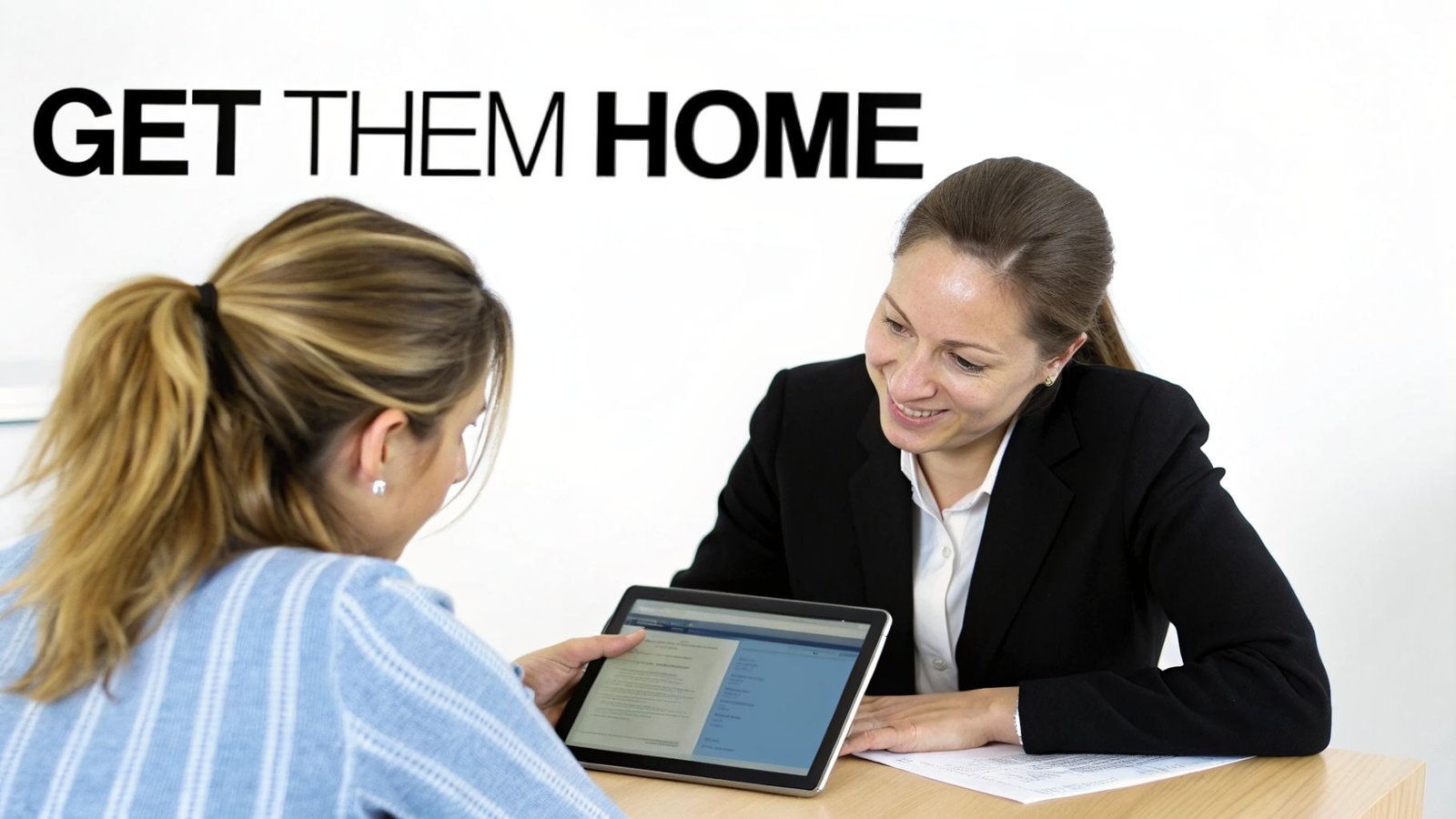 Two women engage in a professional discussion, looking at content on a digital tablet.