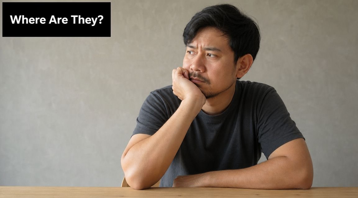 A concerned Asian man sitting at a desk appearing to be waiting or searching for someone.