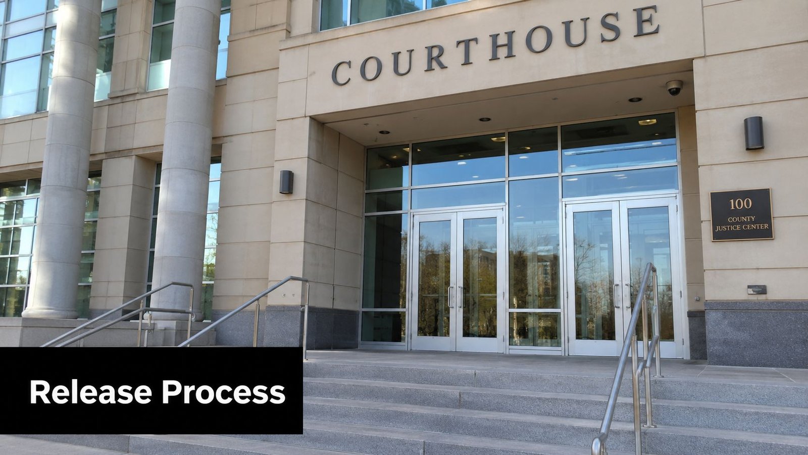 The exterior entrance of a modern stone courthouse building with glass doors and stair steps.